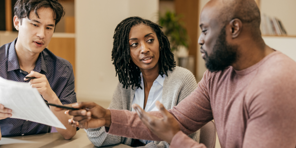 2 men and 1 woman discussing what's on a white piece of paper