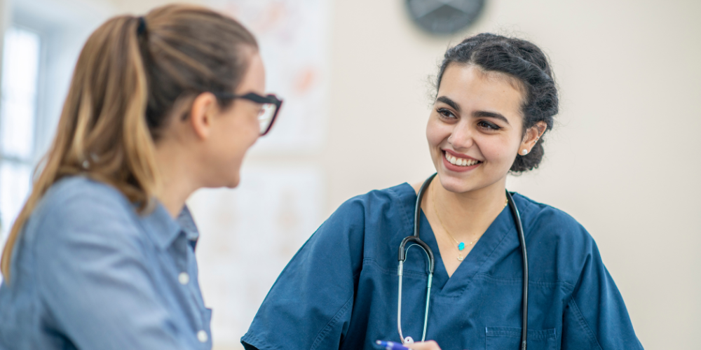 A female nurse sat with a female patient 