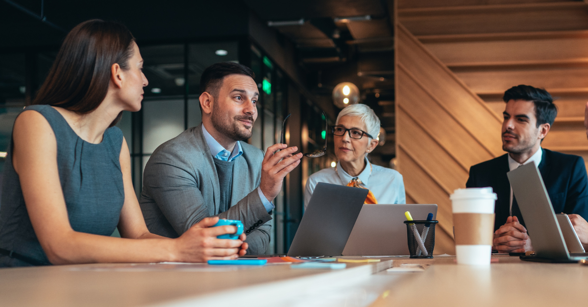 4 people sat around a table discussing the difference between a CTO and CIO