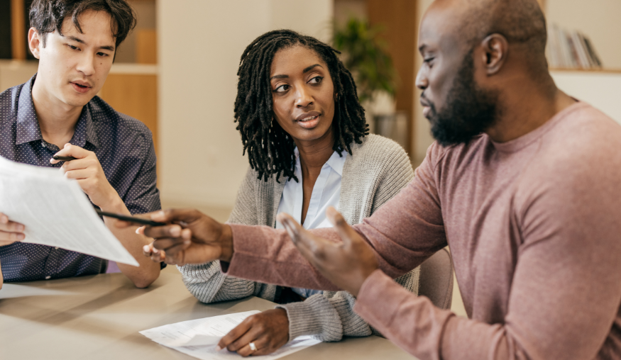 2 men and 1 woman discussing what's on a white piece of paper