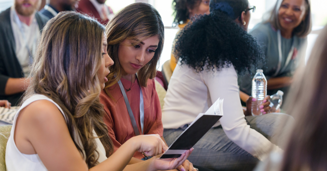 2 women discussing a brochure at an event 