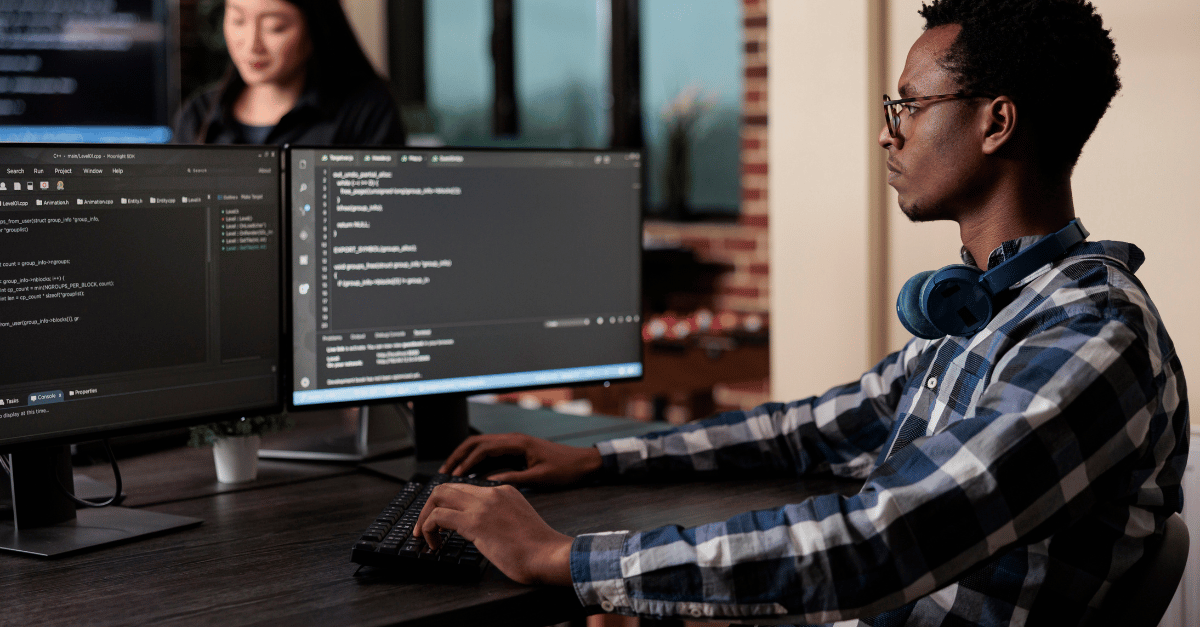 A software engineer analysing code on dual monitors in a modern office setting, emphasising the hands-on evaluation of technology stacks during technical due diligence to identify potential investment risks.